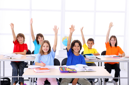 Cute school students raising hands in a modern classroom.