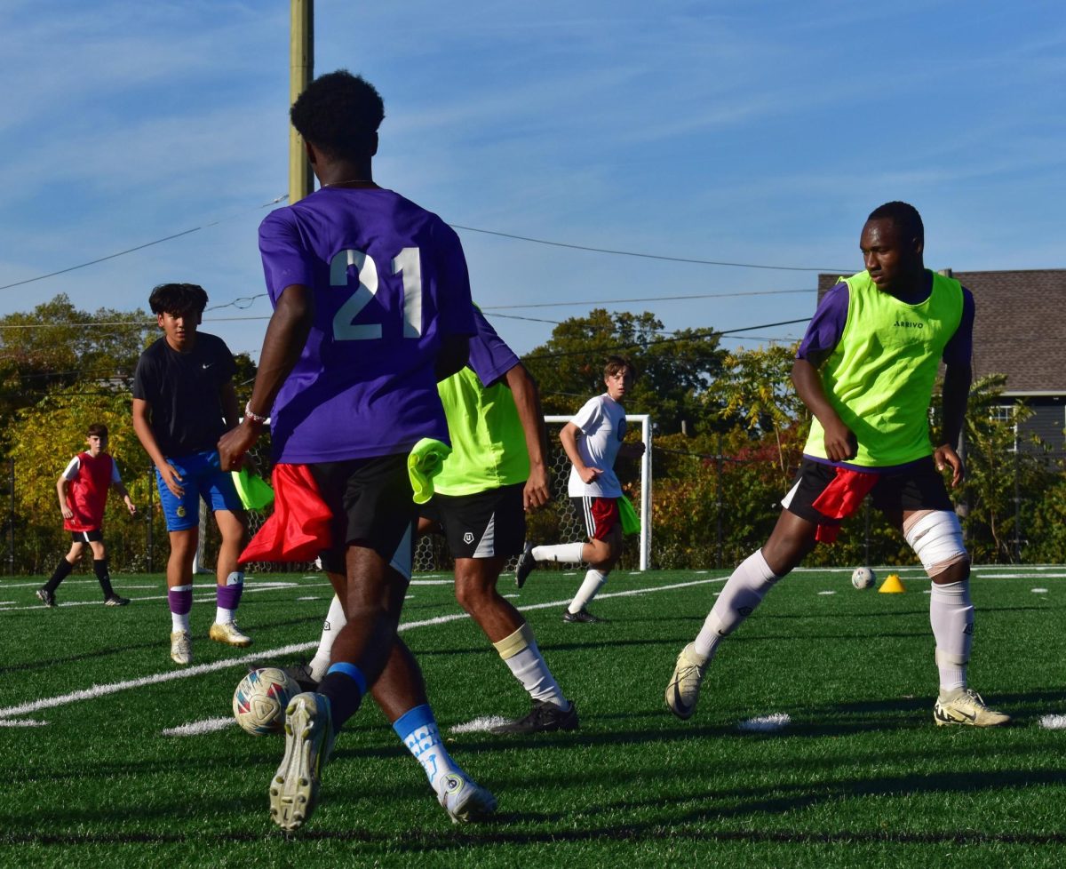 The Boys Varsity Soccer team practicing a mock game in preparing for the playoff season, fighting for the ball between players wearing the yellow, and players wearing the red pinnies.