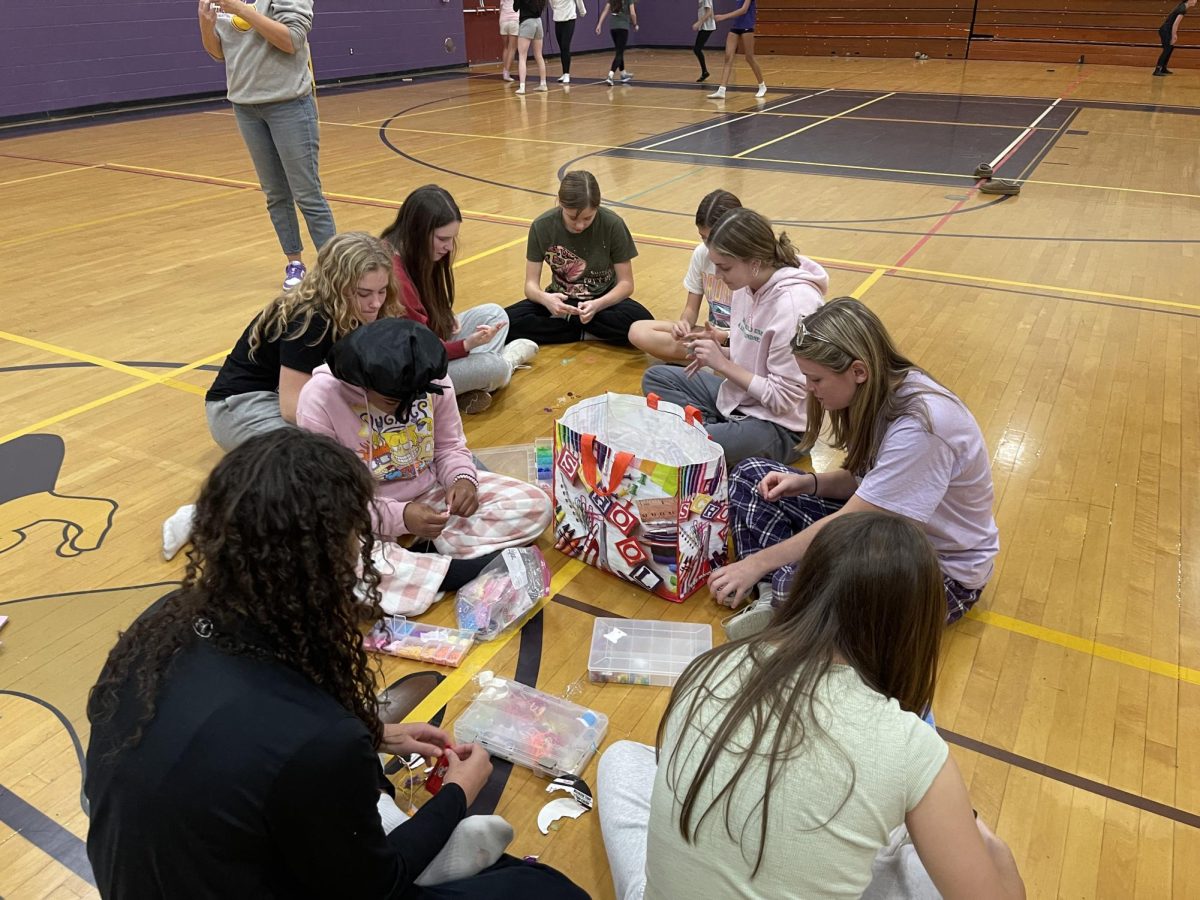 A group of middle schoolers and high schoolers work on making bracelets together.