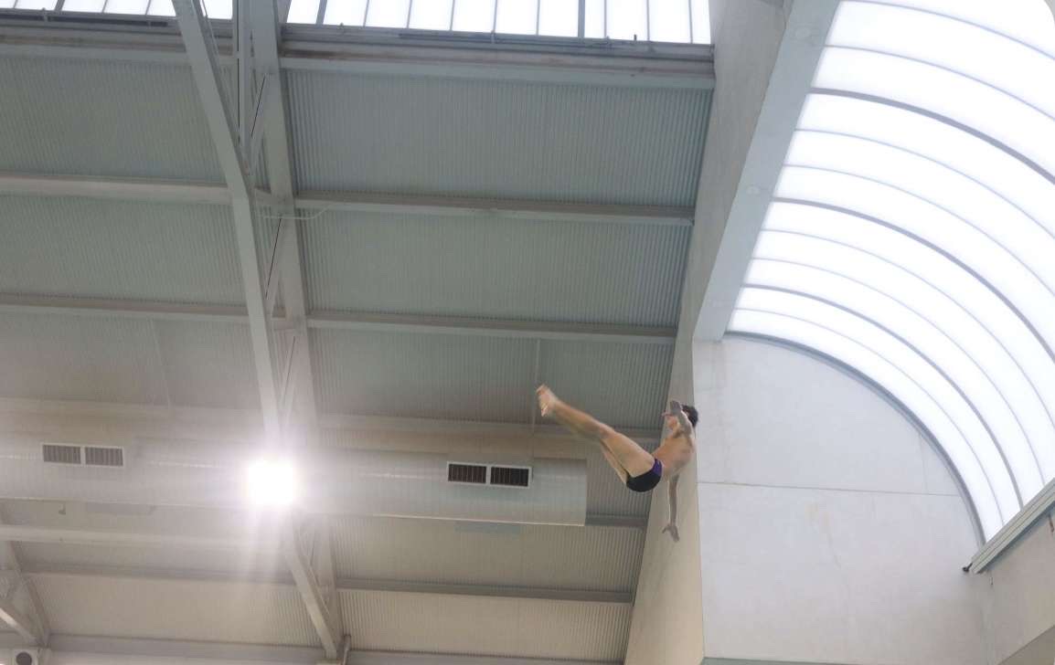 Team Captain Rian Fetting reaching for his legs after jumping off the three-meter diving board