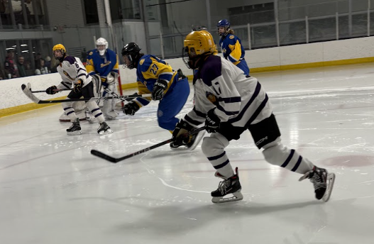 Freddie Showers and Tyler Volcansek chase after the puck, determined to beat an opponent from stealing it