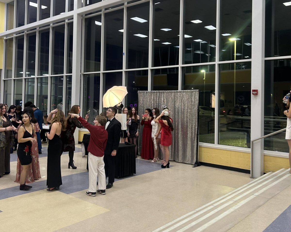 Several students get together and line up to take photos together at the Winter Snowball using a photo booth.