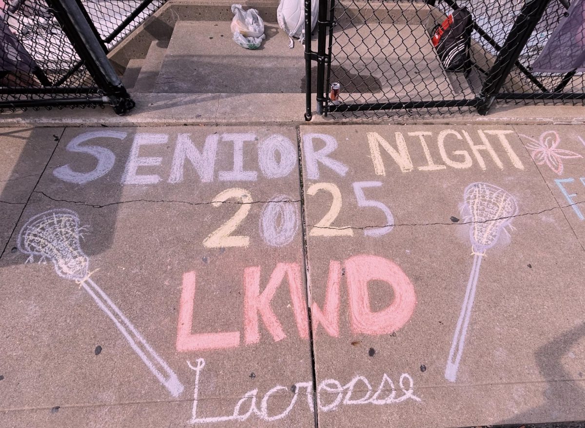 As people walk up to enter the bleachers, the sidewalk is decorated to honor Senior Night