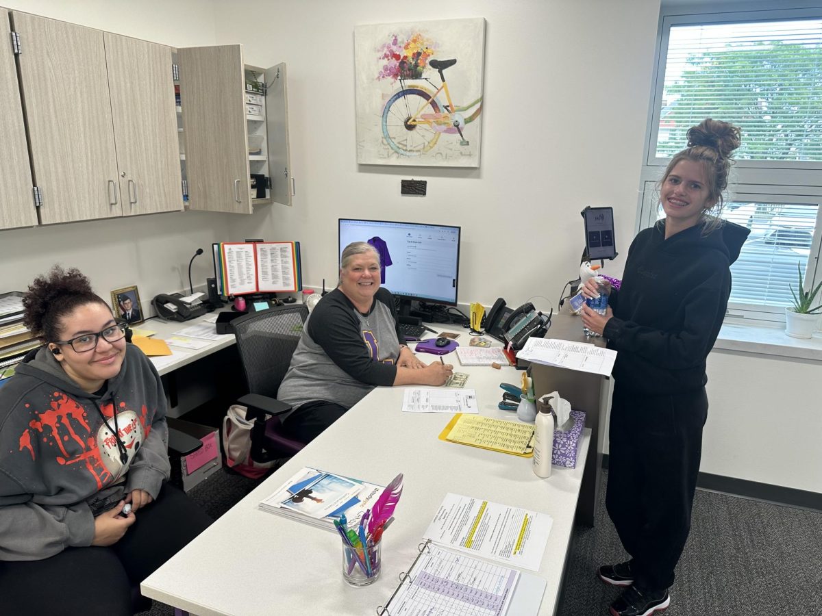 Mrs. Atfield signs out Addison Ward at the front desk of the new FSO, while Nevaeh Keith converses with the two.