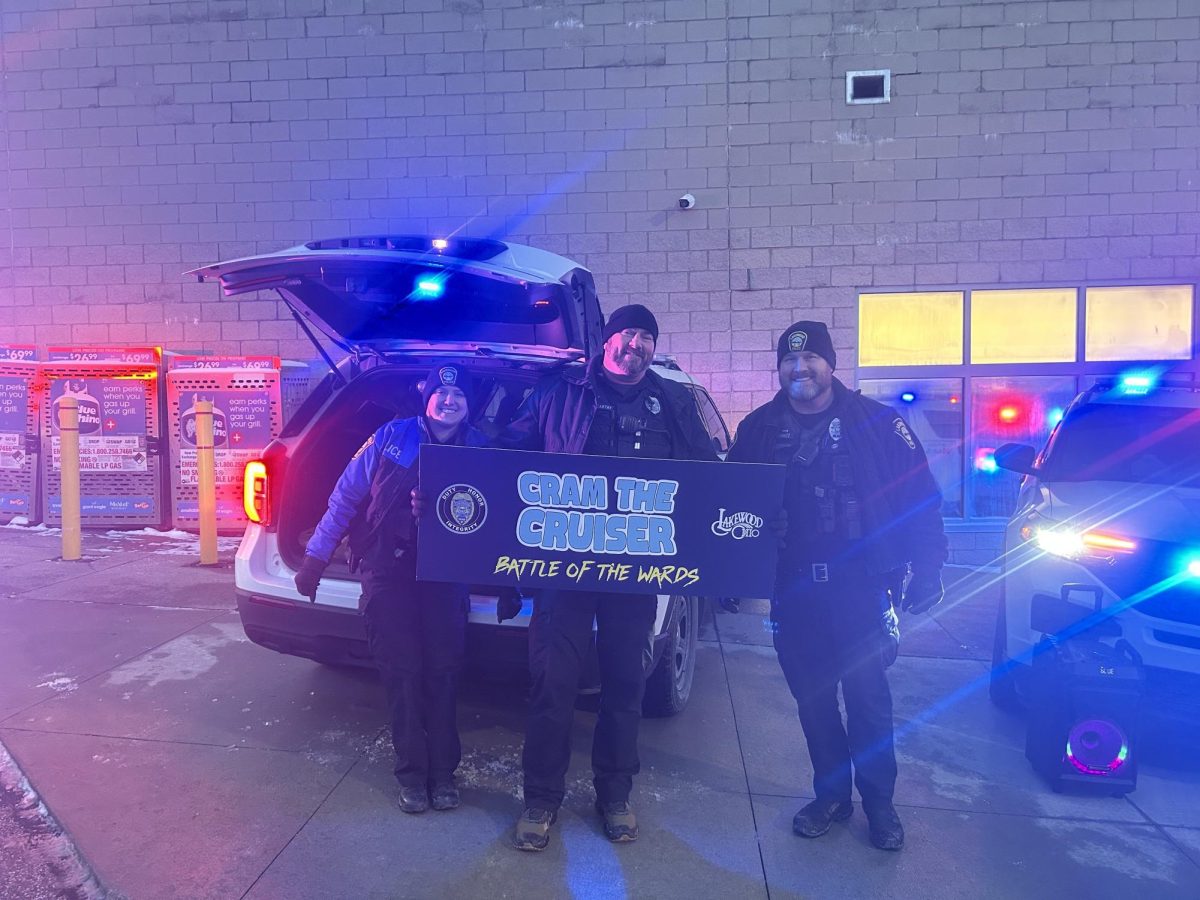 Officers participating in "Cram the Cruiser" pose next to the sign.