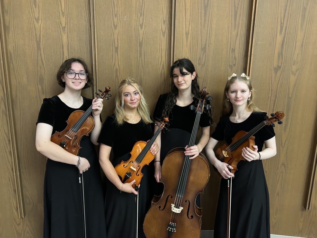 Orchestra students pose with their instruments before a concert.