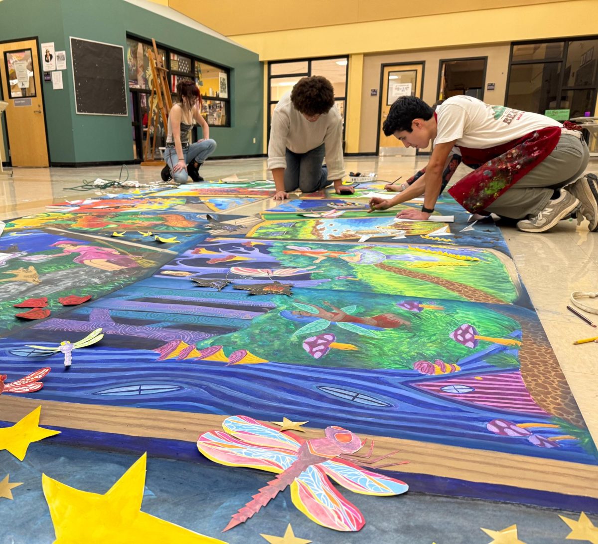 Students work on the mural on the floor.
