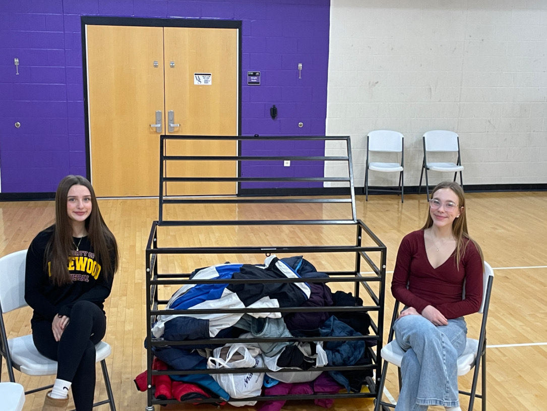 Mia Dugan and Lyla Parkinson collect coats at the door of the girls basketball game.