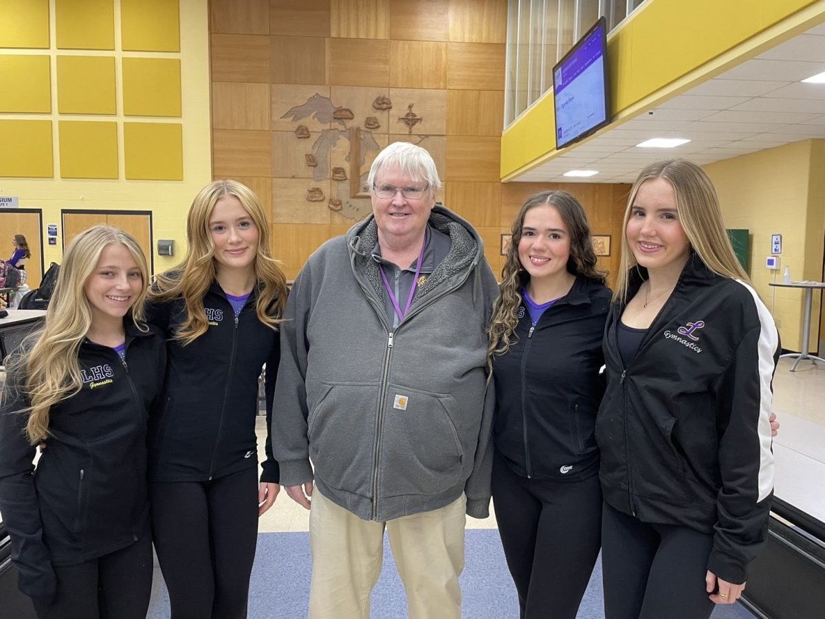 Coach Glunt stands with members of the Lakewood gymnastics team.