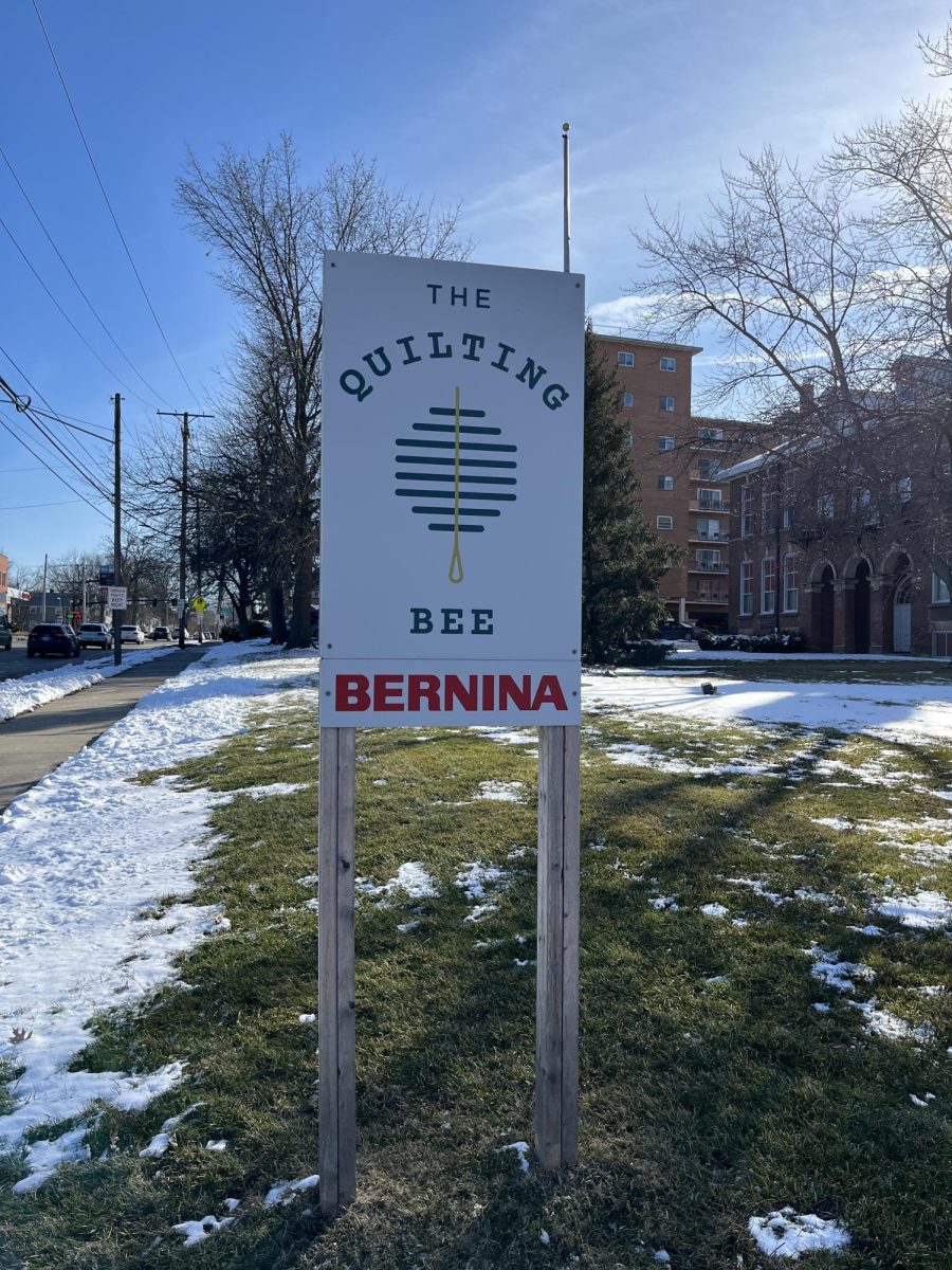 A sign outside the building features The Quilting Bee logo and advertises Bernina sewing machines.
