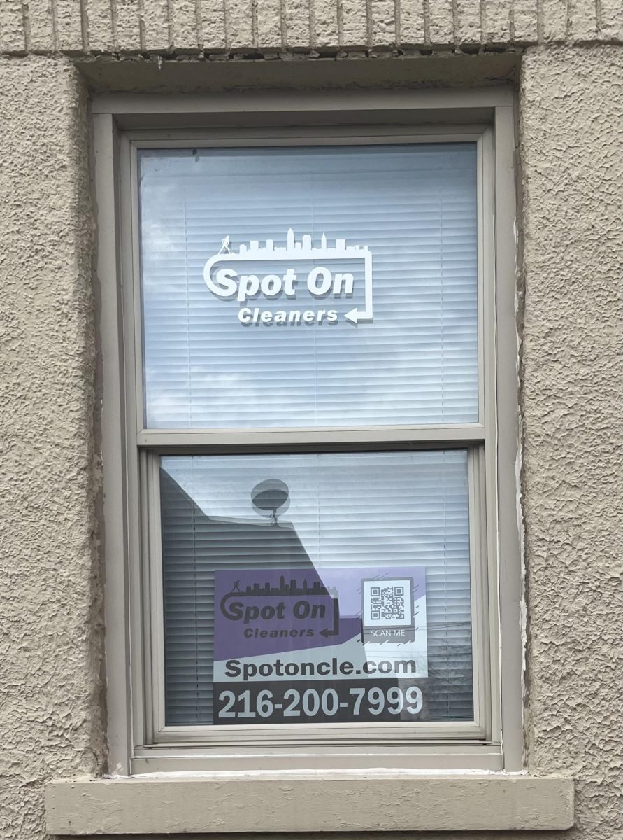 A window on the side of the office featuring Spot On Cleaners's logo, phone number, and QR code.