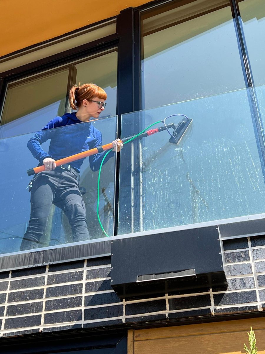 Nugent uses a metal T-bar with a mop attachment to deep-clean a building’s windows.