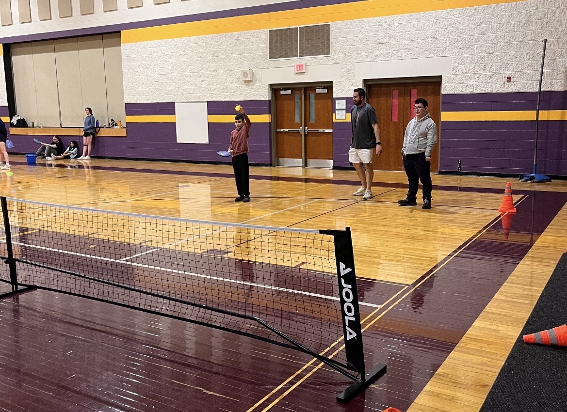 Coach Holesko giving the athletes tips on how to best serve the ball.