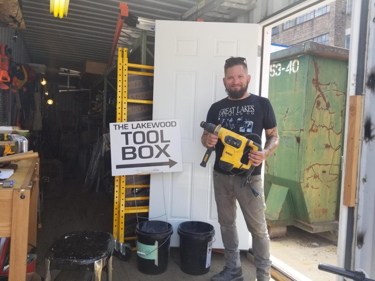 Matt poses next to a sign advertising the Lakewood Toolbox.